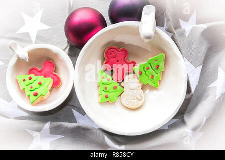 Biscotti di Natale nella forma di verde albero di Natale e pupazzo di neve, con due palle di Natale come decorazione Foto Stock