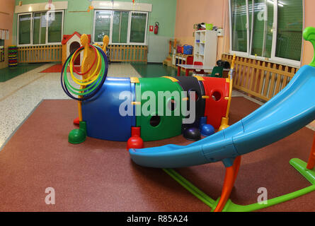 Ampia sala di una scuola materna con molti giocattoli e una slitta in plastica per far giocare i bambini Foto Stock