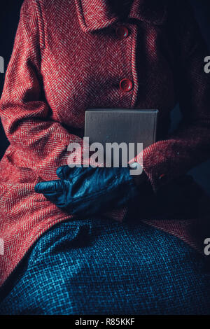 Donna storico in cappotto invernale in possesso di un libro Foto Stock