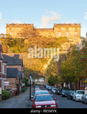 Nottingham Castle che si affaccia su una strada di Nottingham e l'alloggiamento e illuminate dalla luce del sole su una sera d'autunno. Nottingham, Inghilterra, Regno Unito Foto Stock