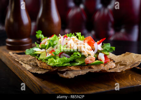 Deliziose bruschette con polpa di granchio nel ristorante dello sfondo. Esclusiva sano cibo servito su una tavola di legno e carta craft Foto Stock