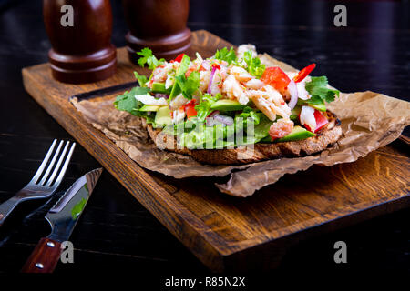 Deliziose bruschette con polpa di granchio nel ristorante dello sfondo. Esclusiva sano cibo servito su una tavola di legno e carta craft Foto Stock