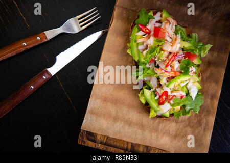 Deliziose bruschette con polpa di granchio nel ristorante dello sfondo. Esclusiva sano cibo servito su una tavola di legno e carta craft Foto Stock