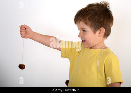 Un giovane bambino ragazzo con conkers Foto Stock