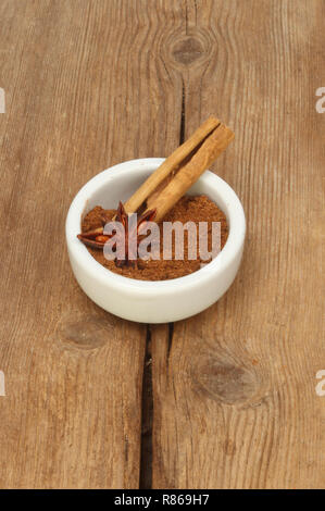 Il cinese cinque spezie con cannella e anice stellato in un ramekin sul vecchio legno rustico Foto Stock