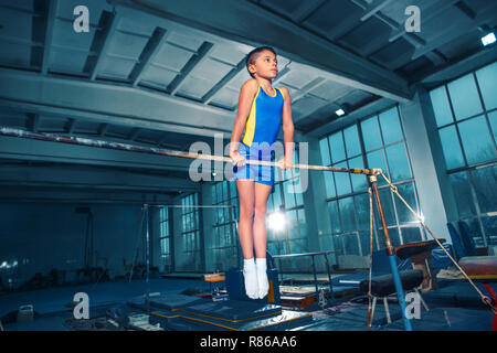 Il ragazzino è impegnata nella ginnastica sport su barre parallele in palestra. Le prestazioni, sport, acrobat acrobatico, esercizio, il concetto di formazione Foto Stock