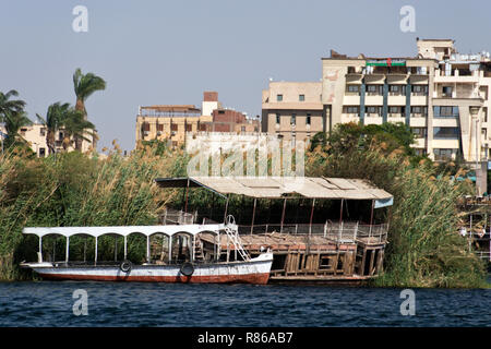 Un egiziano barca ormeggiata in canne accanto a una barca abbandonata, lungo la sponda del Nilo ad Aswan, Egitto. Foto Stock