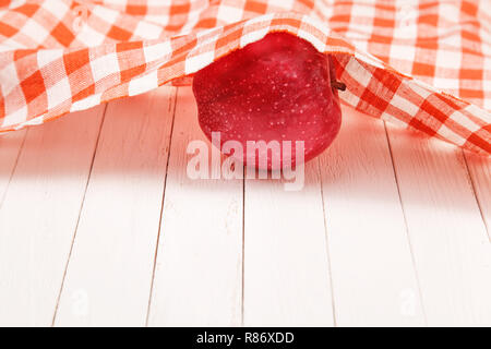 Apple rosso su bianco tavolo ricoperto da una tovaglia Foto Stock