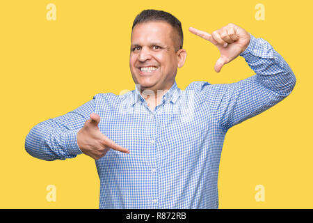 Età media arab business man over isolato sorridente sfondo rendendo il telaio con le mani e le dita con la faccia felice. La creatività e il concetto di fotografia. Foto Stock