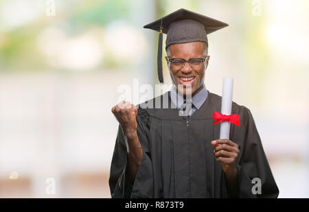 Giovane laureato americano africano uomo grado di contenimento su sfondo isolato urlando orgoglioso e celebrando la vittoria e il successo molto eccitato, cheerin Foto Stock