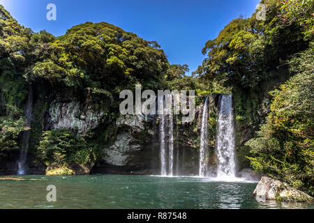 Una cascata nell'isola di Jeju in Corea del Sud in un cielo blu giorno Foto Stock