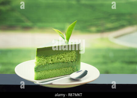 Chiudere di nuovo il tè verde la torta su piastra bianca con la piantagione di tè in background. Foto Stock