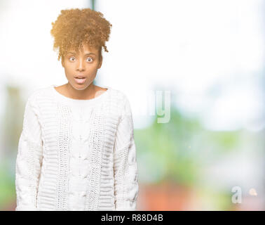 Bella giovane americano africano donna che indossa un maglione invernale su sfondo isolato paura e scioccato con sorpresa di espressione, paura ed entusiasti di f Foto Stock