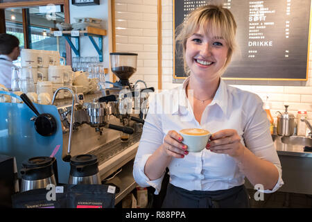 Tromso, Norvegia - Agosto 18th, 2018: una giovane donna barista che mostra un appena fatto cappuccino in un coffee shop in Tromso, Norvegia. Foto Stock