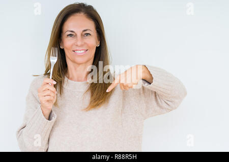 Medio Evo Woman holding forcella di argento metallico isolato su sfondo con sorpresa faccia puntare il dito a se stesso Foto Stock
