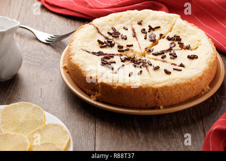 In casa la cheesecake cosparso con scaglie di cioccolato su uno sfondo di legno. Vista laterale Foto Stock