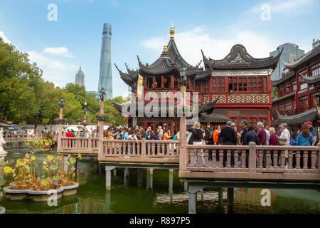 I turisti a piedi attorno a negozi di Yu Yuan (l' Yuyuan) bazaar, Shanghai, Cina. Cielo nuvoloso, turisti sulle passerelle di legno su un laghetto. Foto Stock