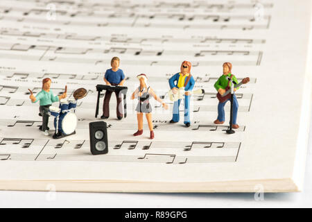 Rock band di persone in miniatura riproduzione di concerto su aprire il notebook musicale con note musicali Foto Stock