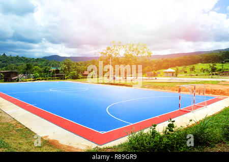 Campo di calcetto o campo di calcio sport outdoor la linea bianca al centro del cerchio e l'obiettivo reti / blu del campo di calcetto in campagna sullo sfondo di montagna Foto Stock