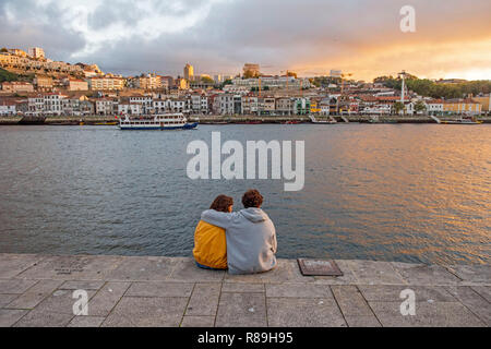 Coppia giovane seduto sulla riva del fiume Douro a Porto, Portogallo. Foto Stock