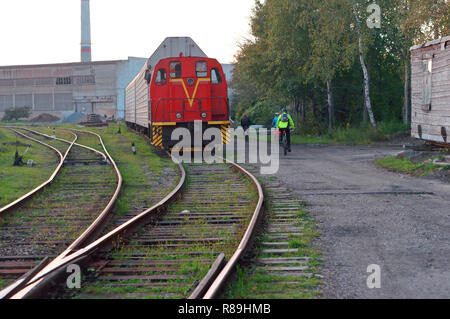 Il 6 ottobre 2018, Kaliningrad, Russia, ciclisti corsa lungo i binari ferroviari, il trenino rosso vale la pena Foto Stock