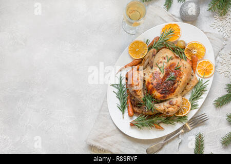 Tradizionale Natale pollo arrosto guarnire arancione, la carota e il rosmarino sul tavolo luminoso. Vista dall'alto. Copia dello spazio. Foto Stock