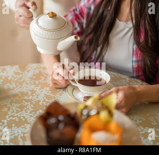 La cerimonia del tè. Versando da tè bianco teiera delicato per la tazza di porcellana. Tempo per la famiglia. Foto Stock