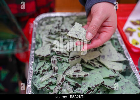 Femmina trattiene a mano su un pezzo di menta verde cioccolato bianco corteccia fatti in casa per Natale Foto Stock