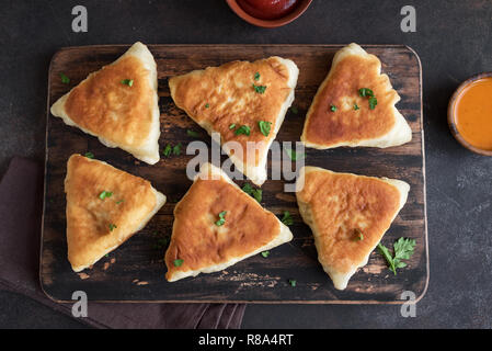 Fritte pasticci di carne, samsa, samosas, echpochmak - Le carni tradizionali torte ripiene o torte vegetariane su sfondo rustico, vista dall'alto. Foto Stock