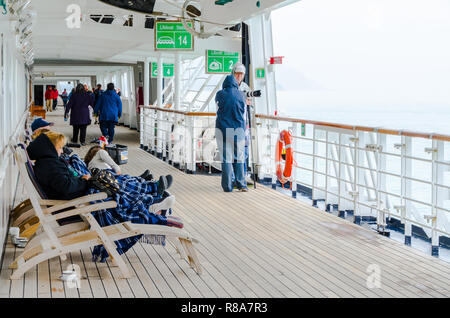 Passeggeri godendo di time out sul ponte durante la stagione fredda vacanza in crociera. I pensionati godendo spensierato stile di vita di viaggio su una nave da crociera. Foto Stock