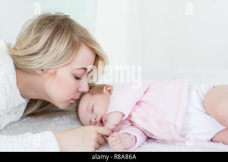 Giovane bella madre mette la sua bimba dormire. maternità concetto, di amore e di cura. Foto Stock