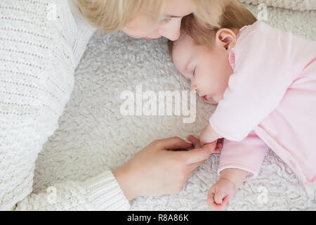 Giovane bella madre mette la sua bimba dormire. maternità concetto, di amore e di cura. Foto Stock