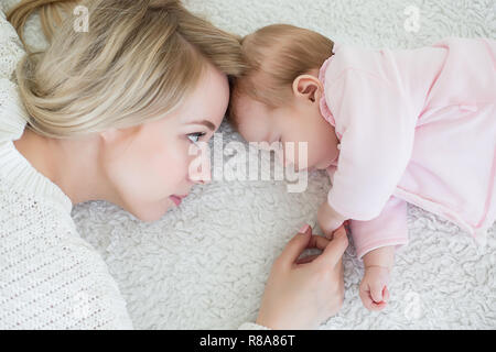 Giovane bella madre mette la sua bimba dormire. maternità concetto, di amore e di cura. Foto Stock