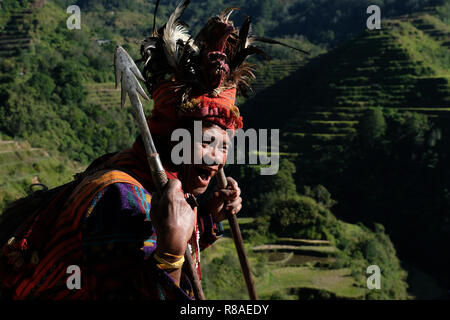 Un anziano uomo Ifugao indossare copricapo ornato con piume e monkey cranio al Banaue terrazze di riso nel nord di Luzon, Filippine. In passato gli Ifugao noto anche come Ifugaw, Ipugao, Yfugao temevano erano cacciatori di teste, così come altre tribù delle regioni montuose del Luzon del nord. Foto Stock