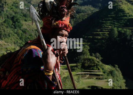 Un anziano uomo Ifugao indossare copricapo ornato con piume e monkey cranio al Banaue terrazze di riso nel nord di Luzon, Filippine. In passato gli Ifugao noto anche come Ifugaw, Ipugao, Yfugao temevano erano cacciatori di teste, così come altre tribù delle regioni montuose del Luzon del nord. Foto Stock