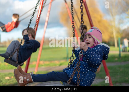 Pre-scuola di età femmina caucasica nel parco giochi sul distributore rotazione Foto Stock