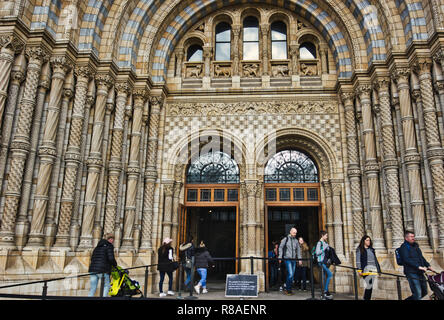 I turisti che entrano ed escono attraverso gli ornati in cotto entrata principale per il Museo di Storia Naturale di South Kensington, Londra, Inghilterra Foto Stock