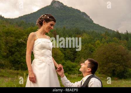 Maschio caucasico sulle ginocchia chiedendo la sua sposa di sposarla davanti alla montagna in Slovacchia Foto Stock
