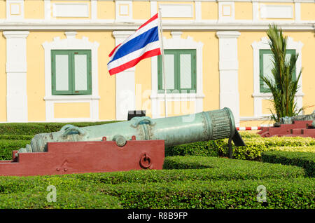 Il vecchio cannone e bandiera tailandese nella parte anteriore del Ministero della Difesa, antico Museo di Artiglieria, Bangkok, Thailandia Foto Stock