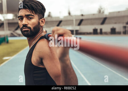 Close up di un atleta in piedi sulla via tenendo un giavellotto sulle sue spalle. Uomo in formazione giavellotto in uno stadio. Foto Stock