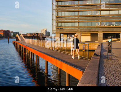 La donna in esecuzione sulla passerella di legno, Kalvebod Brygge (Kalvebod Quay), Vesterbro di Copenaghen, Danimarca e Scandinavia Foto Stock