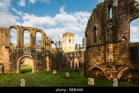 Le rovine dell'Abbazia di Fountains in una bella mattina di autunno come osservata attraverso il fiume Skell a Ripon, nello Yorkshire, Regno Unito. Foto Stock