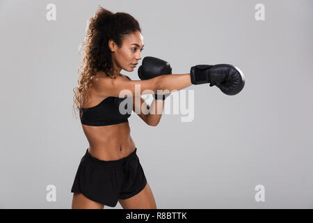 Ritratto di un afro-americano di giovani sportive facendo pugilato isolate su uno sfondo grigio Foto Stock