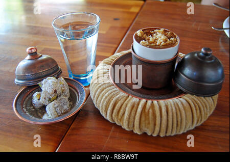 Caffè alla turca con nocciola servito in un bicchiere coperto da un coperchio in rame e impostare su un portabicchiere morbido simile ad un pasha hat. Foto Stock