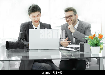 Fotografi qualificati discutere le foto per caricare i file su un computer portatile . Foto Stock