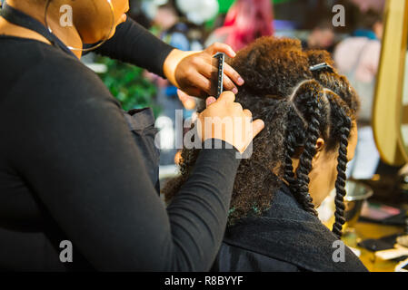 Close up african parrucchiere capelli intrecciati di afro american client femmina nel Barbiere Salone. Il Nero dei capelli sani di cultura e di stile. La terapia con elegante pr Foto Stock