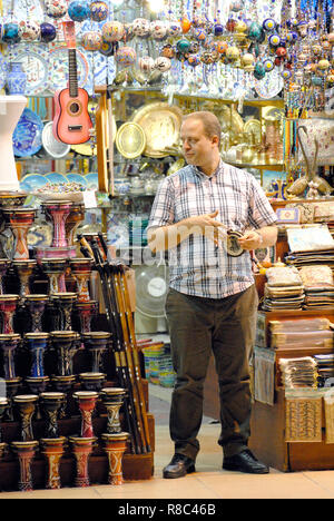 Istanbul, Turchia - 6 novembre 2015. Venditore maschio al Grand Bazaar di Istanbul, tra strumenti musicali. Foto Stock