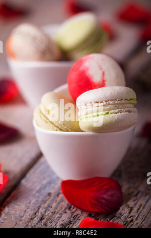 Gustosa macarons e petali di rosa su sfondo di legno Foto Stock