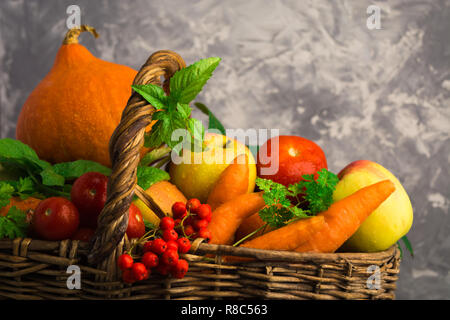 Diversi tipi di frutta e verdura in cesto in vimini su uno sfondo grigio con spazio di copia Foto Stock