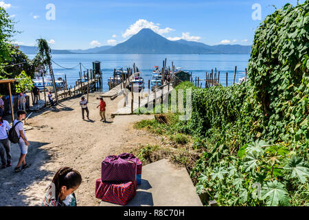 Panajachel, lago Atitlan, Guatemala - 12 Novembre 2018: la gente del posto e i turisti a piedi barche intitolata a villaggi sul lago con San Pedro vulcano dietro. Foto Stock